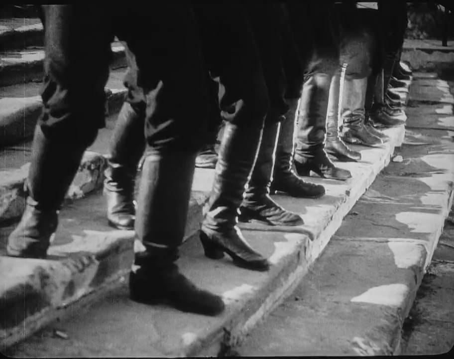 Fotograma em preto e branco: botas de soldados descem em fila os degraus da escadaria de Odessa.
